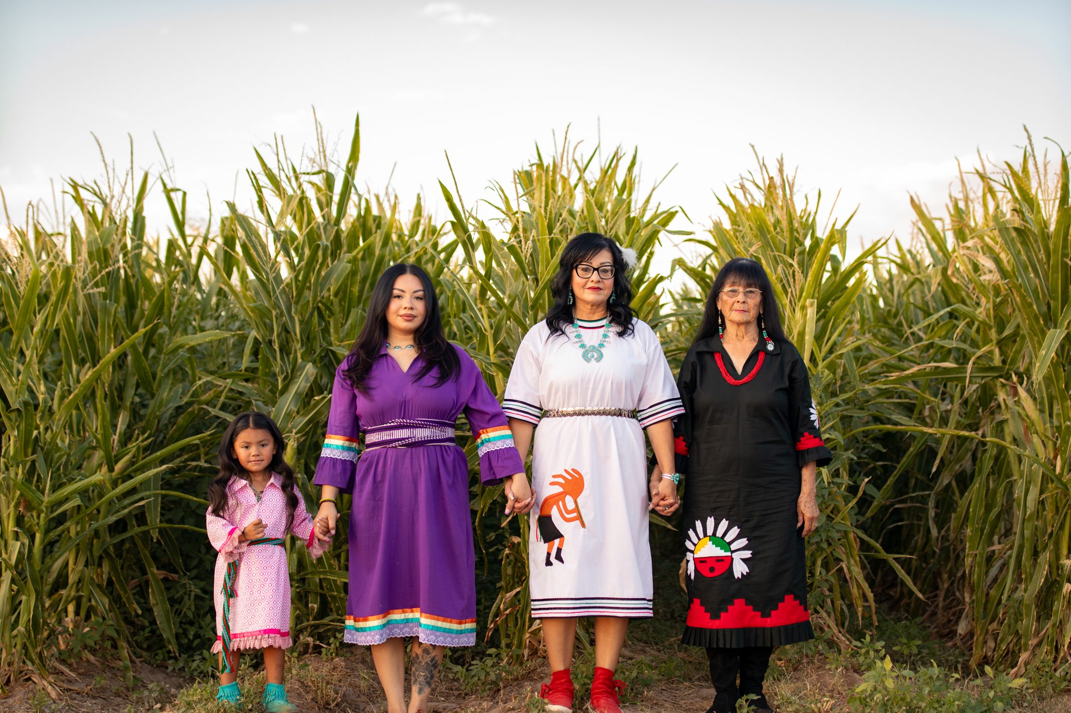 Four generations of Tigua women in traditional dress in a cornfield